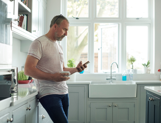 Man in a kitchen scrolling on phone