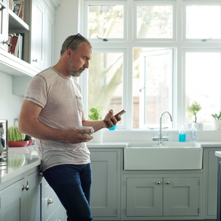Man in a kitchen scrolling on phone