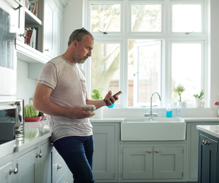 Man in a kitchen scrolling on phone